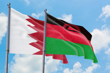 Malawi and Bahrain flags waving in the wind against white cloudy blue sky together. Diplomacy concept, international relations.