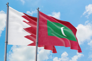 Maldives and Bahrain flags waving in the wind against white cloudy blue sky together. Diplomacy concept, international relations.