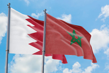 Morocco and Bahrain flags waving in the wind against white cloudy blue sky together. Diplomacy concept, international relations.