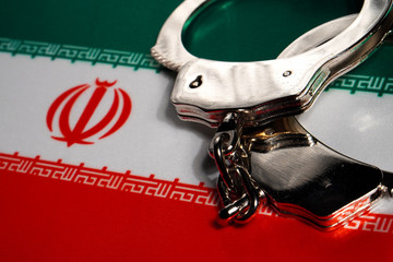 Handcuff on the flag of Iran. Close-up, copy space