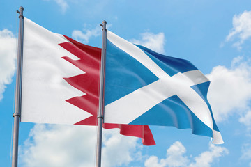 Scotland and Bahrain flags waving in the wind against white cloudy blue sky together. Diplomacy concept, international relations.