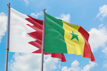 Senegal and Bahrain flags waving in the wind against white cloudy blue sky together. Diplomacy concept, international relations.