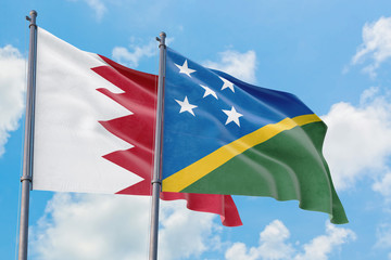 Solomon Islands and Bahrain flags waving in the wind against white cloudy blue sky together. Diplomacy concept, international relations.