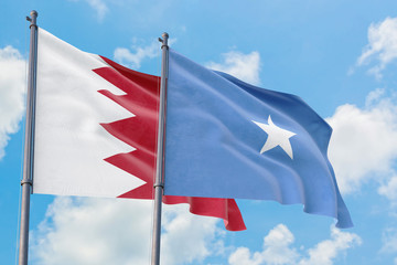 Somalia and Bahrain flags waving in the wind against white cloudy blue sky together. Diplomacy concept, international relations.