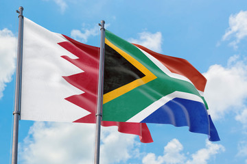 South Africa and Bahrain flags waving in the wind against white cloudy blue sky together. Diplomacy concept, international relations.