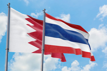 Thailand and Bahrain flags waving in the wind against white cloudy blue sky together. Diplomacy concept, international relations.