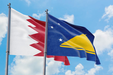 Tokelau and Bahrain flags waving in the wind against white cloudy blue sky together. Diplomacy concept, international relations.