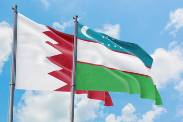 Uzbekistan and Bahrain flags waving in the wind against white cloudy blue sky together. Diplomacy concept, international relations.