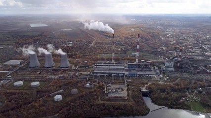 Obraz premium Power plant generating heat and electricity. High pipes and cooling towers are visible. Aerial view.