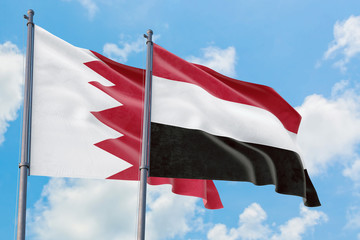 Yemen and Bahrain flags waving in the wind against white cloudy blue sky together. Diplomacy concept, international relations.