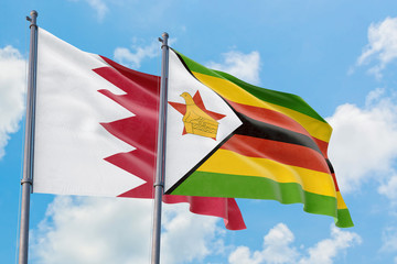 Zimbabwe and Bahrain flags waving in the wind against white cloudy blue sky together. Diplomacy concept, international relations.