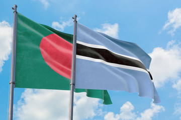 Botswana and Bangladesh flags waving in the wind against white cloudy blue sky together. Diplomacy concept, international relations.