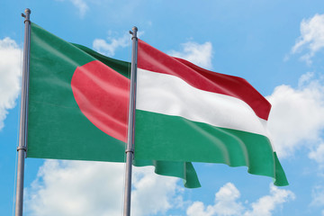 Hungary and Bangladesh flags waving in the wind against white cloudy blue sky together. Diplomacy concept, international relations.