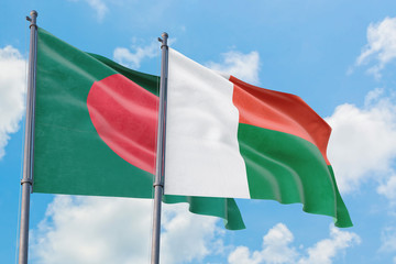 Madagascar and Bangladesh flags waving in the wind against white cloudy blue sky together. Diplomacy concept, international relations.