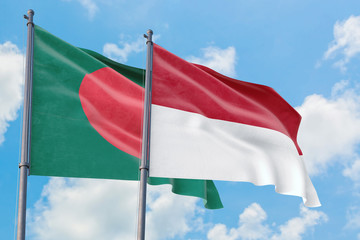 Monaco and Bangladesh flags waving in the wind against white cloudy blue sky together. Diplomacy concept, international relations.
