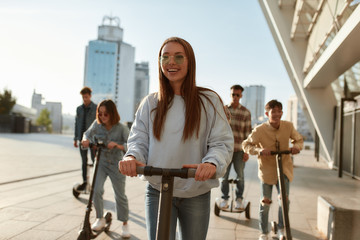 More smiles per hour. A group of friends riding kick scooters and segways on a sunny day