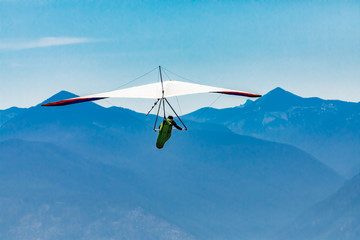 Hang gliding over great mountains. Soaring flight of hang-glider pilot over Kootenay valley...