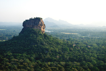 Fototapeta na wymiar Lions Rock surrounded by forest and mountains in background in Sigiriya, Sri Lanka