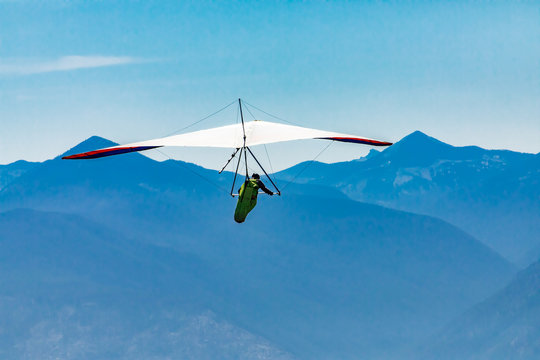Hang gliding over great mountains. Soaring flight of hang-glider pilot over Kootenay valley mountains in Creston, British Columbia, Canada