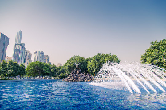 ABU DHABI, UAE - 12 October, 2019: Lush green public garden or children's park at the Corniche with fountain at the Abu Dhabi City.