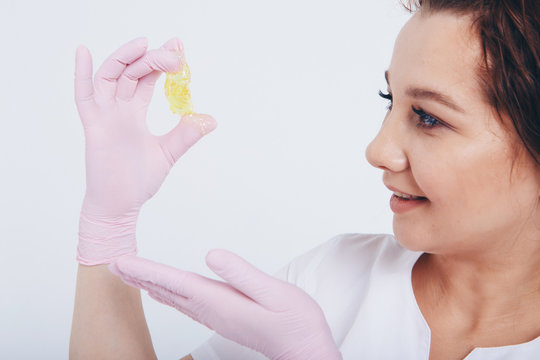 wax for depilation close-up. The girl demonstrates a cosmetic product. The doctor's gloved hand. Sugaring: hair removal with liquid sugar. This is a less painful hair removal with wax replacement