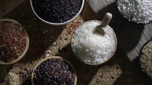 Organic brown rice and asian black riceberry with jasmine white rice in bowl on wooden desk, uncooked products by organic natural food concept, top view