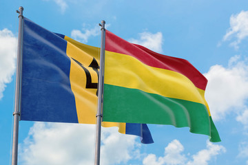 Bolivia and Barbados flags waving in the wind against white cloudy blue sky together. Diplomacy concept, international relations.
