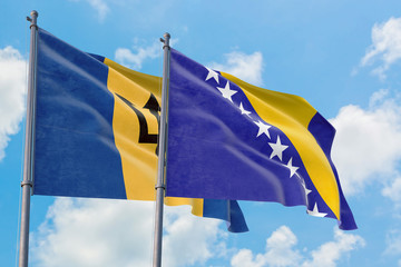 Bosnia Herzegovina and Barbados flags waving in the wind against white cloudy blue sky together. Diplomacy concept, international relations.