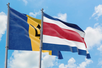 Fototapeta na wymiar Costa Rica and Barbados flags waving in the wind against white cloudy blue sky together. Diplomacy concept, international relations.
