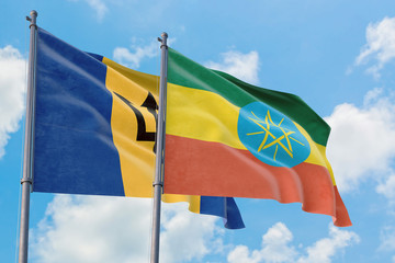 Ethiopia and Barbados flags waving in the wind against white cloudy blue sky together. Diplomacy concept, international relations.