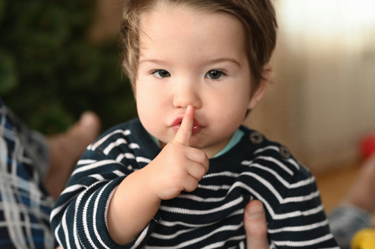 Baby and silence. shows a finger. The child is 0-1 years old. a small child shows a finger with one hand. one year old child portrait.
