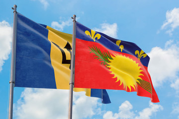 Guadeloupe and Barbados flags waving in the wind against white cloudy blue sky together. Diplomacy concept, international relations.