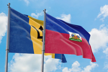 Haiti and Barbados flags waving in the wind against white cloudy blue sky together. Diplomacy concept, international relations.