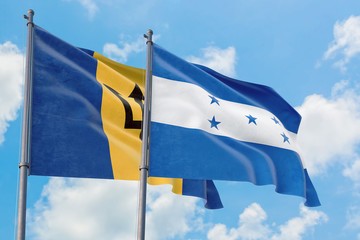 Honduras and Barbados flags waving in the wind against white cloudy blue sky together. Diplomacy concept, international relations.