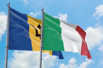 Italy and Barbados flags waving in the wind against white cloudy blue sky together. Diplomacy concept, international relations.
