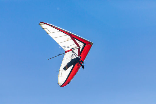 Hang glider soaring against the clear blue sky. View from the bottom to flying hang glider pilot. Recreational weekend activities