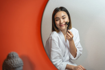 Amazing girl in white bathrobe doing massage for her face