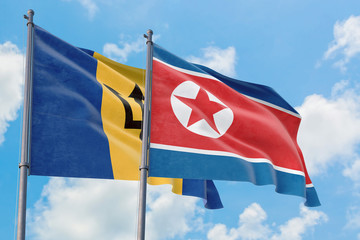 North Korea and Barbados flags waving in the wind against white cloudy blue sky together. Diplomacy concept, international relations.