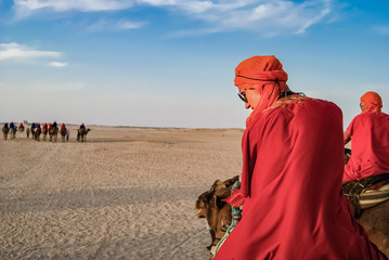 Tourists in the desert on camels. The entertainment of tourists.