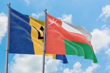 Oman and Barbados flags waving in the wind against white cloudy blue sky together. Diplomacy concept, international relations.