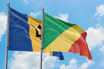 Republic Of The Congo and Barbados flags waving in the wind against white cloudy blue sky together. Diplomacy concept, international relations.