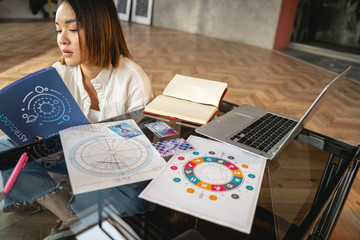 Asian girl is reading her horoscope indoors