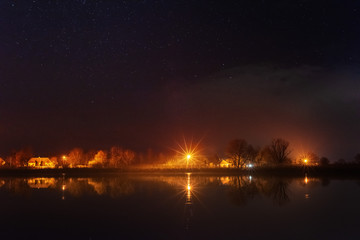 A magical starry night on the river bank with a large tree and a milky way in the sky and falling stars