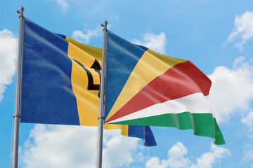 Seychelles and Barbados flags waving in the wind against white cloudy blue sky together. Diplomacy concept, international relations.
