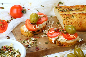 Bruschetta with tomatoes and goat cheese on a white wooden background
