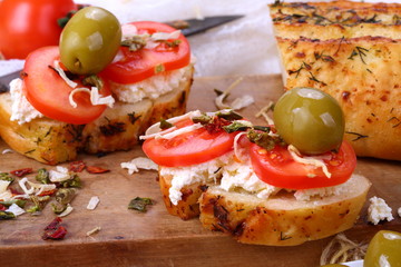 Bruschetta with tomatoes and goat cheese on a white wooden background