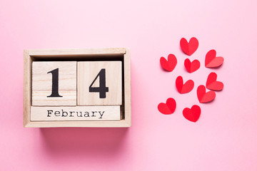 Wooden calendar with the inscription February 14 and with small hearts on a pink isolated background.