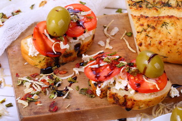 Bruschetta with tomatoes and goat cheese on a white wooden background
