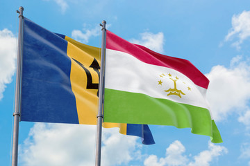 Tajikistan and Barbados flags waving in the wind against white cloudy blue sky together. Diplomacy concept, international relations.