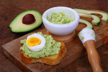 Sandwich with avocado and egg on a wooden table